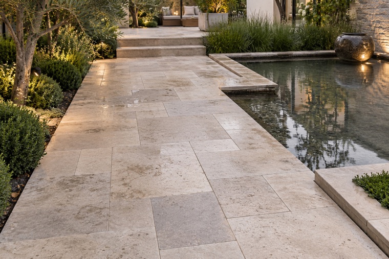 Rain-kissed travertine walkway by reflecting pool